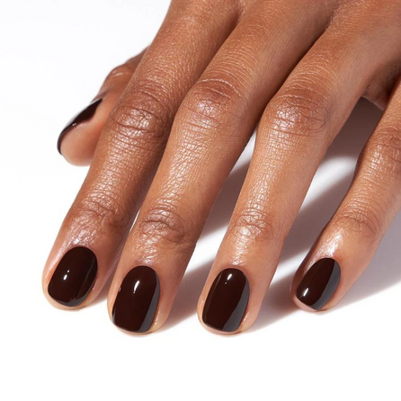 closeup of black cherry colored manicure on a white background