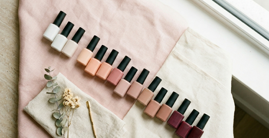 A curated row of gel polish shades from milky white to berry, styled on linen